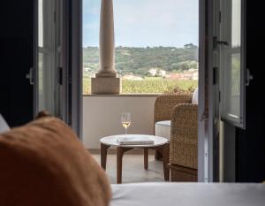 ein Glas Wein auf einem Tisch vor einem Fenster in der Unterkunft &Tales Hotel - Óbidos in Óbidos