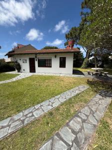 ein weißes Haus mit einem Steinweg davor in der Unterkunft La casita en la playa in Villa Gesell