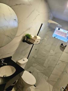Un baño con inodoro, lavabo y espejo. en Easy Access Apartment - Ciudad del Este, en Ciudad del Este