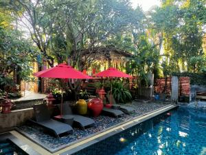 a pool with chairs and umbrellas next to a resort at Villa Thapae in Chiang Mai