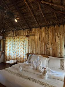 una camera da letto con un grande letto bianco e pareti in legno di Podocarpus Cottages -02 a Naro Moru