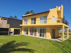 a yellow house with a yard in front of it at La casa del lago in Oliveros