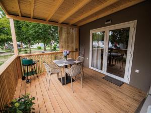 - une terrasse couverte avec une table et des chaises dans l'établissement Lake Serenity Premium Mobile Homes-Two Bedroom, à Mostec