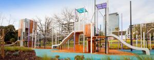 a playground with a slide in front of some buildings at KozyGuru | Box Hill | Elegant City Hideaway in Box Hill