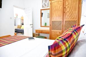 1 dormitorio con 1 cama blanca y armario de madera en Joyces Highview, en Kingstown
