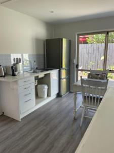 een keuken met witte aanrechtbladen en een tafel en een stoel bij The Hut in Russell