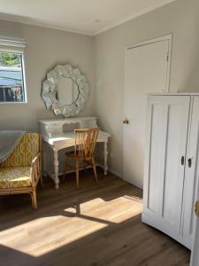 een kamer met een bureau, een spiegel en een stoel bij The Hut in Russell