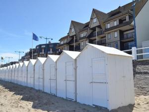 une rangée de cabanes de plage blanches sur la plage dans l'établissement Studio moderne et spacieux au centre de Villers-sur-Mer, proche plage - FR-1-712-61, à Villers-sur-Mer 7 autres photos
