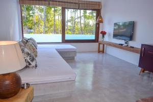 a living room with a white couch and a tv at Casa Marah - Trancoso in Trancoso