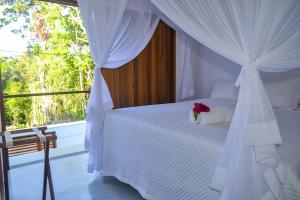 a bedroom with a white bed with a flower on it at Casa Marah - Trancoso in Trancoso +13 photos