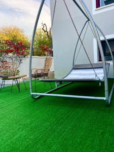 une balançoire sur une pelouse verte avec des chaises dans l'établissement IRIS Boutique Rooms, à Corinthe