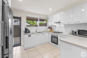 a white kitchen with white cabinets and appliances at Norwood Urban Sanctuary Condo 2b1b free parking in Norwood