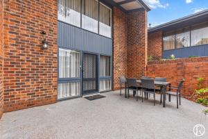 a patio with a table and chairs next to a brick building at Norwood Urban Sanctuary Condo 2b1b free parking in Norwood