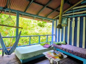 カプルガナにあるLa Bohemia Capurganáのベッド1台付きの部屋、ハンモック付きのポーチが備わる部屋です。