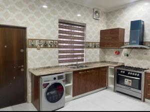 a kitchen with a stove and a dishwasher at AlphaDreams Villa in Magodo