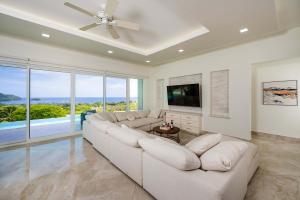 ein Wohnzimmer mit einem weißen Sofa und einem Fernseher in der Unterkunft Ocean View Oasis Infinity Pool in Gated Resort in Coco