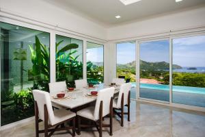 ein Esszimmer mit Tisch und Stühlen und Fenstern in der Unterkunft Ocean View Oasis Infinity Pool in Gated Resort in Coco + 24 Fotos
