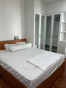 una camera da letto con un letto con lenzuola bianche e uno specchio di Tòa nhà SHP 12 Lạch Tray, tầng 2209 a Hai Phong