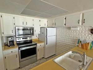a kitchen with white cabinets and a stove and refrigerator at 439 Ala Wai, 119 condo in Lake Valley