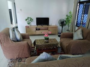 a living room with two couches and a tv at Kulae Homestay in Nadi
