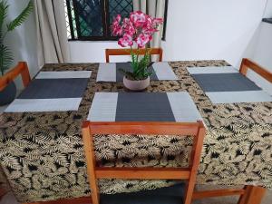 a table with two chairs and a vase of flowers on it at Kulae Homestay in Nadi