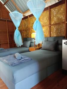 - une chambre avec 2 lits et des rideaux bleus dans l'établissement Dahla Lanta Hut, à Ko Lanta