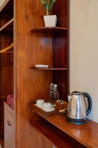 una estantería de madera con un hervidor de agua y tazas. en Narada House Ubud, en Ubud