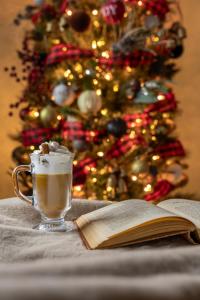 Uma xícara de café e um livro aberto ao lado de uma árvore de Natal. em Adora in the Pines with Axe Throwing em Flagstaff