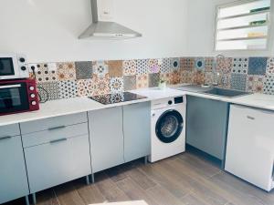 a kitchen with a washing machine and a microwave at Letoilevelli in Salazie