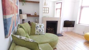4 bedroom home - N17 في لندن: غرفة معيشة مع كرسي أخضر ومدفأة