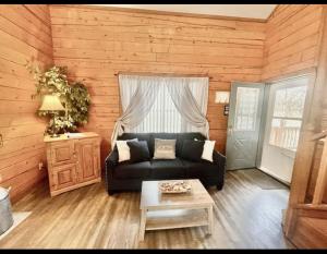 un soggiorno con un divano nero e un tavolo di Enchanted Farmhouse Cabin a Branson
