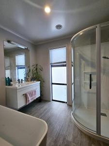 ein Badezimmer mit Dusche, Waschbecken und Spiegel in der Unterkunft Pōhutukawa House Pohara in Pohara
