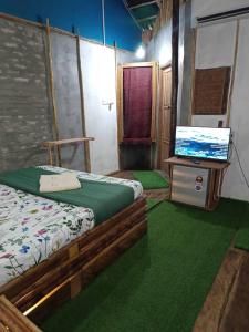 a bedroom with a bed and a flat screen tv at Cahaya Wooden Studio in Pantai Cenang