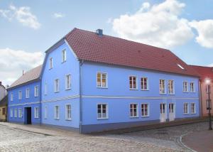 niebieski budynek z czerwonym dachem na ulicy w obiekcie Ferienwohnungen Malow w mieście Röbel