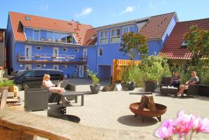 grupa ludzi siedzących na dziedzińcu z niebieskim budynkiem w obiekcie Ferienwohnungen Malow w mieście Röbel