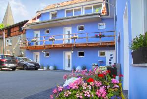 a blue building with flowers in front of it at Ferienwohnungen Malow in Röbel