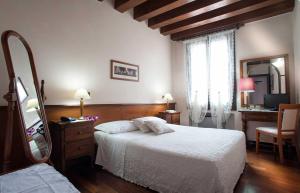 a bedroom with a bed and a dresser and a mirror at Hotel Al Castello in Bassano del Grappa