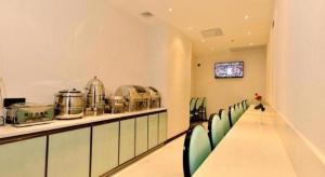 einen langen Tisch mit grünen Stühlen in einem Zimmer in der Unterkunft Xana Hotelle Guangzhou Tiyuxi Road Metro Station Branch in Guangzhou