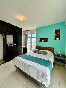 ein Schlafzimmer mit einem großen Bett mit einer blauen Wand in der Unterkunft Charming and Family With a pool and ocean view, 3 blocks from the beach, with 2 TVs and Netflix in Boca del Río