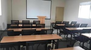 une salle de classe vide avec des tables, des chaises et un écran dans l'établissement City Comfort Inn zhongshan Lihe Square Walmart, à Zhongshan