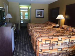 a hotel room with three beds and a television at Executive Inn and Suites Longview in Longview