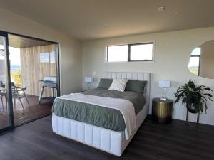 a bedroom with a large bed with a table and a dining room at Golden Ridge Retreat in Otorohanga