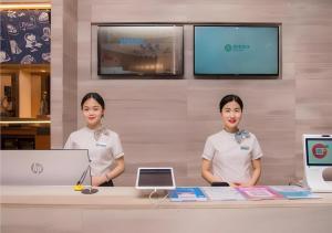 deux femmes debout derrière un comptoir dans un magasin dans l'établissement City Comfort Inn Liuzhou Wuxing Walking Street Zhonghuan Tower, à Liuzhou