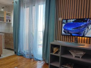 ein Wohnzimmer mit einem TV und blauen Vorhängen in der Unterkunft Magnolia Lux Apartments in Sokobanja