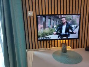 einen TV an einer Wand mit einem Tisch und einem sidx sidx in der Unterkunft Magnolia Lux Apartments in Sokobanja + 6 Fotos