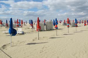 un montón de sombrillas y sillas en la playa en Un Homme Et Une Femme, en Deauville
