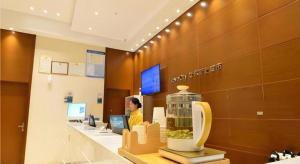 uma pessoa em um escritório com um caixa registradora em City Comfort Inn Wuhan Qingshan Jianshi Qingyiju Metro Station em Wuhan