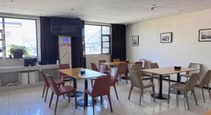 una sala da pranzo con tavoli e sedie e una TV di City Comfort Inn Shiyan Wudang Mountain a Danjiangkou