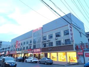 un grand bâtiment avec des voitures garées devant dans l'établissement Shell Hotel Zaozhuang Xinchang Road Bada Market, à Zhaozhuang