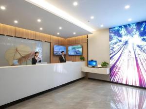 un hall avec deux personnes debout à un comptoir dans l'établissement GreenTree Inn Express Shandong Zaozhuang Shizhong District Huashan Road Ginza, à Zhaozhuang